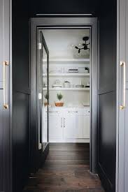 The centerpiece, topped with a trio of crystal glass pendants, is made of a distressed wood base in green tones and neoclassical carvings and a cream granite. White Kitchen Cabinets Black Doors Design Ideas