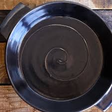 Shiny black baking dish with handles by Zane Wilcox. In some light, it  gives a metallic shimmer. Available in store and online