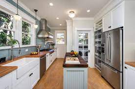 Large kitchen featuring a center island with a peninsula set on a hardwood flooring lighted by pendant and recessed lights. 8 Narrow Kitchen Islands With Function To Spare