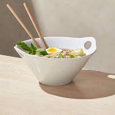 Modern asian serving shape in white porcelain rests bamboo chopsticks in the cutout handles. Kai 11 Noodle Bowl With Chopsticks Reviews Crate And Barrel
