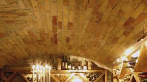 Petite cave à vin à l'ancienne avec murs en briques rouges et meuble de rangement en bois. Une Cave A Vin Au Sous Sol