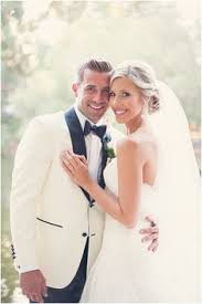 Up Close Look At A Black White Tux Contrasted With All White Bridal Gown Photo C White Tuxedo Wedding Groom And Groomsmen Style Groom And Groomsmen Attire