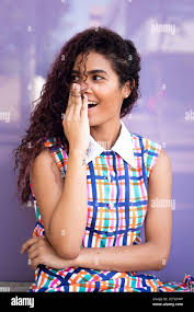 Portrait Of Charming Young Ethnic Young Woman With Curly Hair Tilting Head And Looking Away Against Colorful Glass Wall Stock Photo Alamy