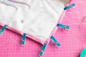 Vor dem einfassen der decke mit dem schrägband setzen sie noch zwei schlaufen an, durch die so hat die decke an dieser stelle etwas weniger stoff. Diy Set Babydecke Blog Alles Fuer Selbermacher
