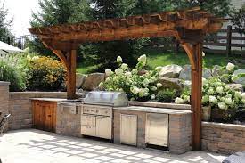 Split face travertine counter features a fridge, stainless steel sink, blaze grill, and storage compartments. Backyard Kitchen With Pergola Novocom Top