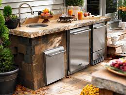 This setup features a gas grill, sink, refrigerator, travertine flooring, and a pergola overhead for shade. Outdoor Kitchen With Grill And Refrigerator Novocom Top