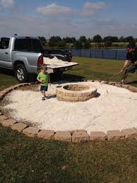 The seating area is blended well with the surrounding landscape by using a stone ledge and some accent pillows. Fire Pit With Pea Gravel And Pavers Fire Pit Landscaping Paver Fire Pit Backyard Fire
