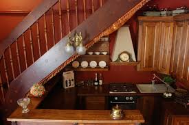 Blue mirrored pantry cabinets with mosaic gray marble backsplash tiles next to a staircase with ornate metal railing. 7 Cool Kitchens Placed Under The Stairs Shelterness