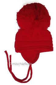 Baby clothes and wooden toys on light blue background. Satila Of Sweden Purl Knit Huge Pom Hat Red Petit Posh