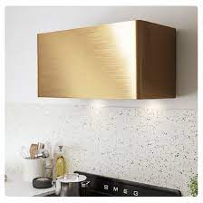 White and gold french range hood designed at a cooktop designed with mosaic accent tiles, an antique swivel arm pot filler and a thermador dual range. Gold Brass Range Hood Modern Kitchen Range Hoods Kitchen Range Hood Brass Range Hood