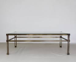 The tabletop is fully handmade out of genuine teak and provides a stable and secure surface on which you can place your drinks, vases, fruit bowls, or decorative items. Glass Coffee Table In Brass Colored Metal Frame 103829