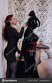 Sexy woman with her latex rubber slave in mask playing at home in bdsm  Stock Photo by ©agnadevi 321387854