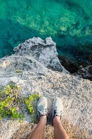 Feet Of A Man Looking Down From A Cliff Into The Ocean Water By Jovo Jovanovic