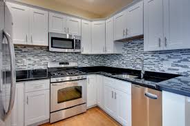By breaking up the upper and lower cabinets and adding in a medium shade of gray to the bottom ones, this kitchen is anything but drab. Design White Cabinet Kitchen Backsplash Ideas