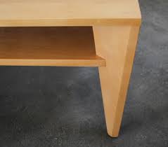 A medium walnut toned solid maple constructed coffee table with lower storage shelve and to each end a woven caned riser sitting on conical legs. Modernist Conant Ball Coffee Table
