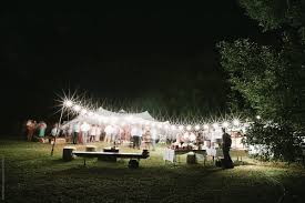 Outdoor weddings come with additional caveats and pitfalls, but if you follow these tips, you'll be consider timing your outdoor wedding for sunset where your guests will see you take your vows. Outdoor Wedding Reception At Night Time By Seth Mourra Stocksy United