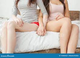 家中卧室里的女同性恋夫妇坐在床上，手紧握着库存图片. 图片包括有生活方式, 人们, 有吸引力的, 夫妇- 176302423