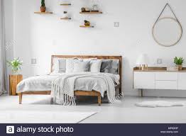 Da sich jedoch auch das boxspringbett durch ein solches polster auszeichnet, kann es. Komfortabel Gross Holz Bett Mit Bettwasche Kissen Und Decken Nachttisch Neben Runden Spiegel Hangen An Einer Weissen Wand In Einem Hellen Schlafzimmer Innenraum Und Stockfotografie Alamy