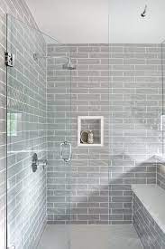 White and gray hexagon shower tiles designed in a horizontal stripe finish completed with two shower niches and a glass shower partition. Glossy Gray Shower Wall Tiles With Light Gray Hexagon Shower Floor Transitional Bathroom