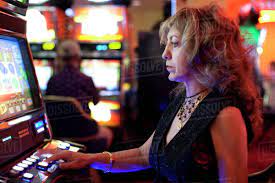 Caucasian woman playing slot machine in casino - Stock Photo - Dissolve