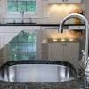 Gray kitchen island is topped with white quartz countertop and corner sinks in silstone helix quartz with suede finish on each end of island paired with gold gooseneck faucets flanking double dishwashers concealed behind gray. 1