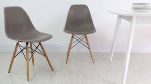 Scandinavian style in a neutral dining room featuring a gallery wall of modern black and white artwork, a wood table, white eames style chairs, and a contemporary chandelier. Dsw Eames Chair Replica Novocom Top