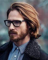Man With Glasses Blonde Hair Blue Striped Shirt Denim Coat Long Hairstyles For Men Long Hair Styles Men Boys Long Hairstyles Long Hair Styles