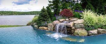 Whether it be a modern or natural theme, we believe a swimming pool. Pool With Water Feature And Infinity Edge Looking Out On The Lake Pool Waterfall Pool Landscaping Swimming Pool Waterfall