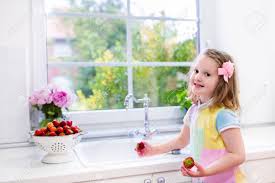 cute little girl washing fruit in