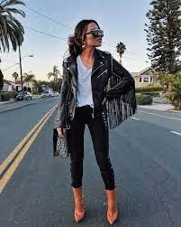 A Black Leather Biker Jacket With Fringes On The Sleeves Is Styled With A Basic V Neck White Fringe Jacket Outfit Leather Jackets Women Leather Jacket Outfits