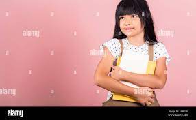 Asian little kid 10 years old holding book for going to school at studio  shot isolated on pink background, Happy child girl hugging textbooks  dictiona Stock Photo - Alamy