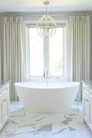 Due to strict building codes for wet environments, the chandelier must be at least 3' from the edge of the tub or shower. Gray Curtains Behind Tub Transitional Bathroom