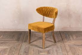 The chair itself has a wingback shape with a high back and flared arms. Velvet Dining Chairs Retro Style Seat Peppermill Interiors