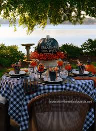 A halloween table setting with a burgundy tablecloth, metallic hammered chargers, black candles and a chic floral centerpiece a moody wedding tablescape with black table runners and napkins, a textural floral table runner, black candles and puple plates This Way To Trick Or Treating Halloween Tablescape Home Is Where The Boat Is