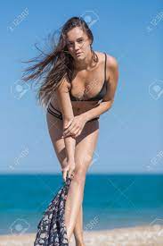 Long Haired Young Woman In Black Bikini Posing Against Sea. Attractive Girl  Undressing On Beach Looking At Camera Фотография, картинки, изображения и  сток-фотография без роялти. Image 86145502