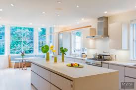 The large kitchen island in the middle of the white flooring has a thick marble countertop and wooden cabinets and drawers that have the same. Cambridge Contemporary Kitchen In Victorian Home Divine Design Center