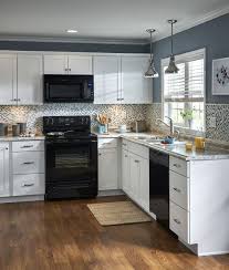 White Cabinetry And A Mosaic Tile Backsplash Contrast With Black Appliances An Black Appliances Kitchen Kitchen Cabinets Kitchen Cabinets With Black Appliances