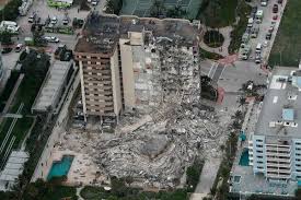 A large plume of smoke and dust is seen shooting into the air as the wing of the building. 1u M2nnt7uumvm