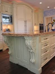 Kitchen island with dual apron sink and bridge faucet across from a stainless steel stove with pot filler below a distressed gray french hood with corbels. 34 Corbels Ideas Corbels Kitchen Design Kitchen Inspirations