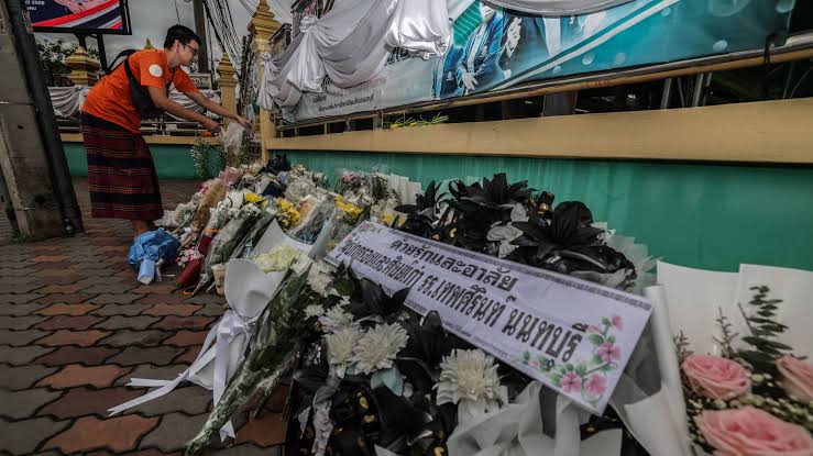 Thai officials and mourners gather at a funeral site following the recent school shooting tragedy.