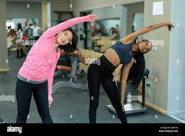 Schlanke schwarze Afro-amerikanische Fitnesstrainer und schöne Asiatin  Übung gemeinsam in der Turnhalle Stockfotografie - Alamy