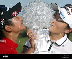 Japan's golfers Ai Miyazato, left, and Rui Kitada, right, pose with their  trophy after winning the Women's World Cup of Golf trophy at the The Links  in Fancourt Country Club in George,