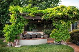 Weathered Orange Tiles With Brick Edging Under Lush Vine Covered Pergolas With Barbecue And Wood Storage And Ceiling Fan White Pergola Pergola Designs Patio