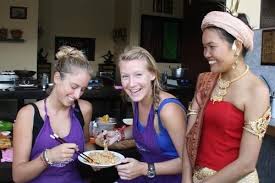 Founder May With Two Cooking Class Students Wearing Purple Aprons Together Holding A Plate Vegetarian Cooking Classes Vegan Cooking Classes Thai Cooking Class
