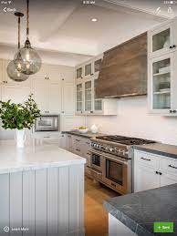 White and black kitchen features a white kitchen island with white quartz countertops and goodman hanging lamps. Reclaimed Wood Hood Reclaimed Wood Kitchen Wood Kitchen Hood Kitchen Range Hood