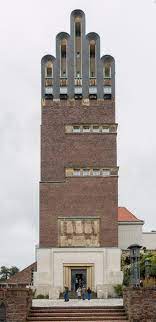 Mathildenhöhe die mathildenhöhe darmstadt ist ein ensemble aus hochzeitsturm, ausstellungsgebäude, museum künstlerkolonie, platanenhain und künstlerhäusern. Joseph Maria Olbrich Hochzeitsturm Darmstadt 1908 Facade Architecture Tower Building Architecture Poster