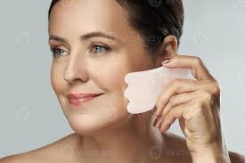 belle femme d'âge moyen faisant un massage du visage avec une pierre rose  gua sha 16291626 Photo de stock chez Vecteezy