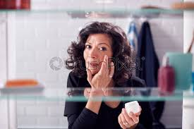 Prepping to get ready for the day means time grooming in the bathroom. View Through Bathroom Cabinet Of Mature Businesswoman Getting Ready For Stock Photo Crushpixel