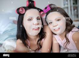Mom and daughter with facial mask on their faces looking in the mirror  Stock Photo - Alamy