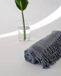 It has a classic rectangular shape and a negative monogram on the reverse side. Nomad Beach Towel Stone Grey Lush Palm